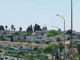 A quiet suburban neighborhood with residential houses, palm trees, and road infrastructure under a clear summer sky photo