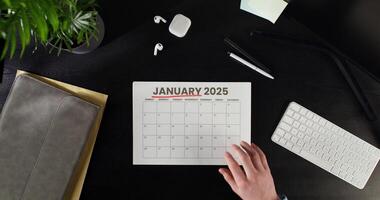 woman highlights date in a calendar while sitting at a table. Planning while working in the office. Close-up photo
