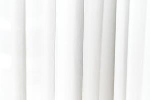 Abstract white textile background features soft vertical folds and subtle shadows creating clean elegant pattern ideal for design backdrop or copy space photo