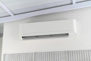 Offering comfortable cooling and climate control, modern white air conditioner unit sits mounted wall indoors. essential technology provides relief from heat, creating pleasant environment photo