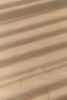 Natural warm wood texture features diagonal shadows and parallel light stripes creating an abstract background pattern on smooth brown surface. detail shows subtle wood grain of organic material photo