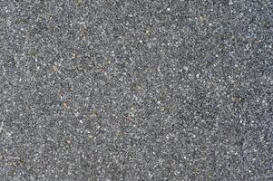 Granular dark grey abrasive texture forms detailed close up surface background. Uniform rough pattern material appears across full frame ideal for graphic design photo