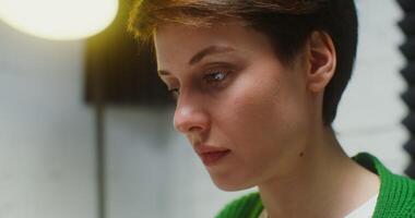 Side view of the face of a young woman of European appearance with a short haircut, with a concentrated look working at the computer, close up photo