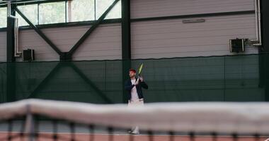 A young dark haired man of European appearance plays big tennis, hitting the ball with a racket over and over again, gracefully bouncing with each racket hit photo