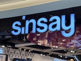 Warsaw, Poland - May 22, 2025 Sinsay brand store sign illuminated in blue, showcasing modern retail design and vibrant atmosphere in a shopping mall environment photo