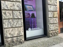 Warsaw, Poland - May 22, 2025 Motorola storefront featuring a vibrant advertisement for Windows 11, showcasing modern technology and urban architecture with a textured stone wall photo