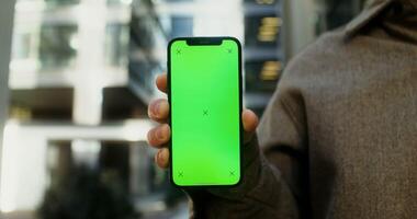 Close up of a mobile phone with a screen forward in the hands of a young man, no face. Copy space, green screen, chroma key, mockup. in 4k, red komodo photo