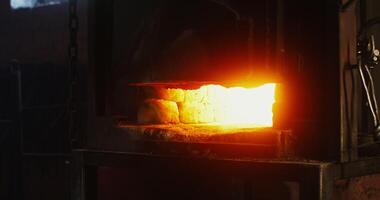 A blacksmith places a metal blank in a burning furnace, close up of burning fire, man's face is not visible, an unrecognizable person. Blacksmith workplace, iron forging workflow. 4k , red komodo photo