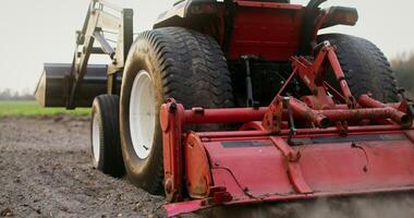 Close up of a tractor with a plow plowing a field on an autumn day, filming from behind, the plowed land flies out from under the plow photo