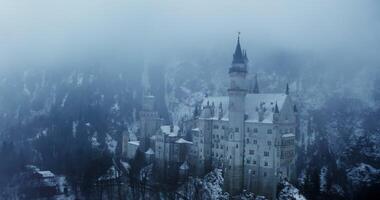 Overview of Hohenzollern Castle from a dynamic motion quadcopter, bird's eye view close up footage on a winter day. Foggy haze over castle, located on top of a hill overgrown with spruce forest photo