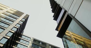 Bottom view of high rise office buildings with large windows. Sky between glass skyscrapers. in 4k, red komodo photo