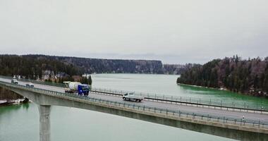 A view of a narrow automobile bridge thrown across the river to the hills overgrown with spruce forest, filming on a winter day photo