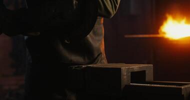 A blacksmith in protective equipment saws off part of a metal stick using an angle grinder, metal sparks fly in different directions, close up, no face, unrecognizable person. 4k , red komodo photo