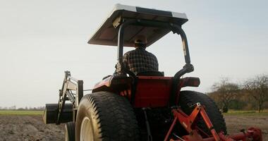 A young European looking farmer turns a tractor around and begins to drive along a new row, plowing a field on an autumn day and turns around, checking the quality of work photo