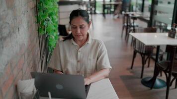 A woman in a coffee shop is enjoying her time working remotely while surrounded by the atmosphere of the coffee shop. video