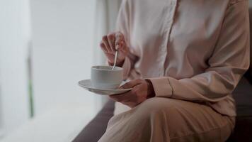 A person savoring a peaceful moment, delicately stirring a cup of coffee or tea in a serene and intimate setting, encapsulating the essence of tranquil relaxation. video