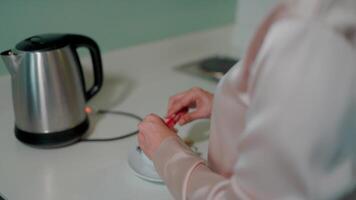 A close-up of a woman preparing tea bags next to a fancy electric kettle, capturing the everyday simplicity of that moment. video