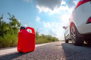 Red reserve canister on road with empty car waiting for refueling photo