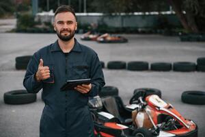 Digital ,tablet, quality control. Man,,, is outdoors, kart racing conception photo