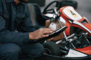 Digital tablet, quality control. Man ,,is outdoors, kart racing conception photo
