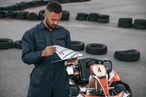 With notepad in hands. Man is,, outdoors, kart racing conception photo