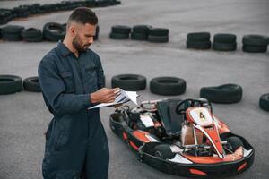 With notepad,, in ,hands. Man is outdoors,, kart racing conception photo