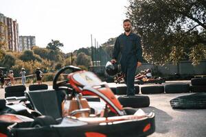 Walking by the vehicle. Man ,is, outdoors,, kart racing conception photo