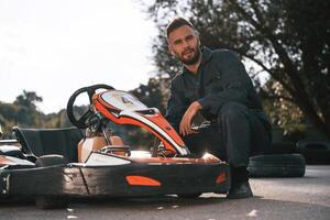 Technician ,,is ,looking at the vehicle. Man is outdoors, kart racing conception photo