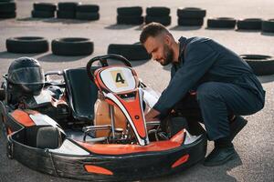 Technician, is, looking at the vehicle. Man is outdoors, kart racing conception photo