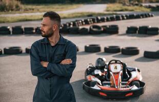 Standing with arms crossed... Man is outdoors, kart racing conception photo