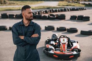 Standing with arms crossed. Man ,is outdoors, kart racing conception photo