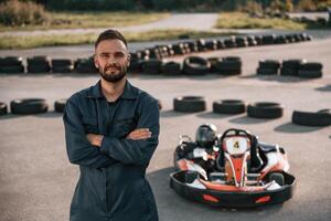 Standing with ,arms, crossed. Man is outdoors, kart racing conception photo