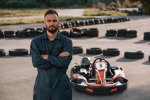 Standing, with arms crossed.. Man is outdoors, kart racing conception photo