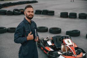 Shows, thumb up, ready to go. Man is outdoors, kart racing conception photo