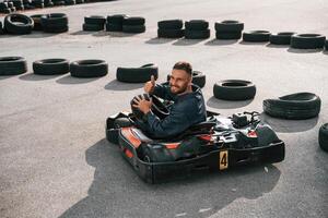 Looks, behind,, while riding. Man is outdoors, kart racing conception photo
