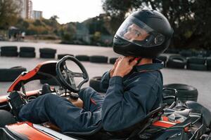 Side ,,view, wearing the safety helmet. Man is outdoors, kart racing conception photo