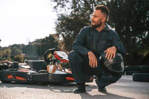 Handsome, positive man is outdoors, kart racing conception photo