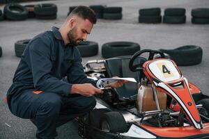 With ,notepad in hands. Man is outdoors, kart racing conception photo