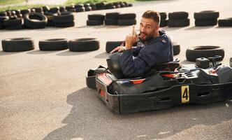 Looks behind, while riding. Man is outdoors, kart racing conception photo