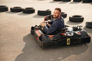 Riding, and looking behind. Man is outdoors, kart racing conception photo