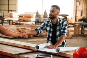 Having a deal, handshake. Two workers are in the industrial wooden warehouse photo