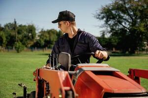 Front view, working, driving., Man is with utility tractor with grass cutter and aerator equipment on the field photo