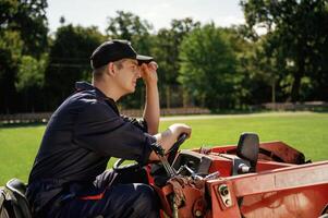 Man is with, utility tractor, with grass cutter and aerator equipment on the field photo