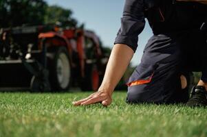 Quality control, touching,, the, grass. Man is with utility tractor with grass cutter and aerator equipment on the field photo