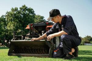 Checking ,the ,cutters. Man is with utility tractor with grass cutter and aerator equipment on the field photo