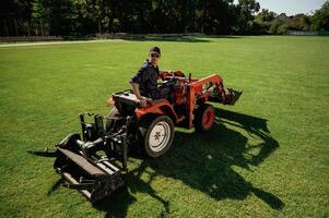 Loan, work. Man, is with utility tractor with grass cutter and aerator equipment on the field photo