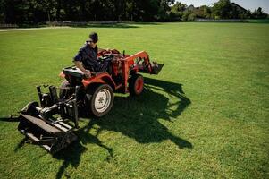 Loan ,work. Man is with, utility tractor with grass cutter and aerator equipment on the field photo