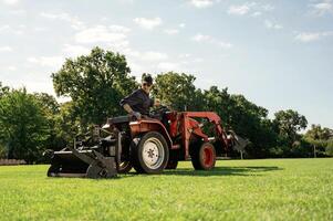 Loan work... Man is with utility tractor with grass cutter and aerator equipment on the field photo