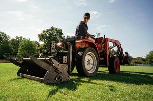 Loan ,work., Man is with utility tractor with grass cutter and aerator equipment on the field photo
