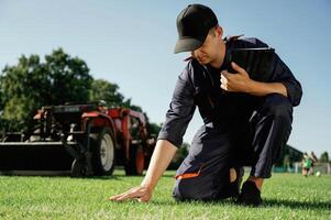 Touching ,the grass, quality control. Man is with utility tractor with grass cutter and aerator equipment on the field photo